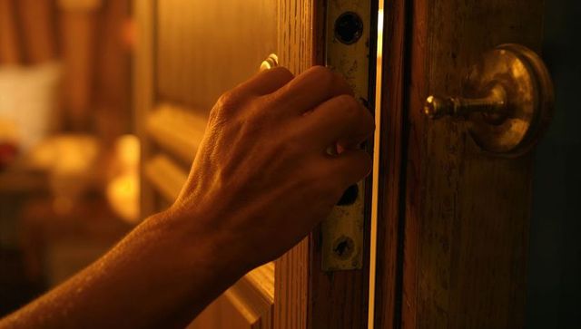Right hand turning antique mortise lock on wooden door in warm amber interior light