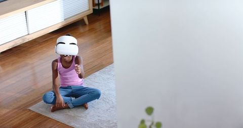 African american teen exploring virtual reality at home wearing white vr headset