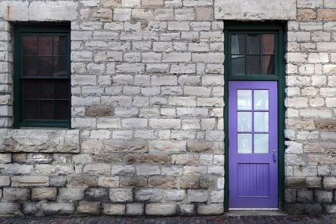 Purple Door with Green Frame on Rustic Stone Wall