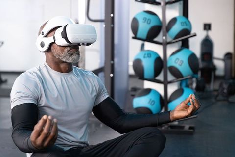Mature african american man meditating in gym using white vr headset for mindful fitness