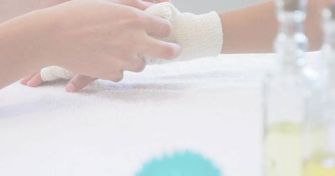 Caregiver wrapping child wrist with gauze bandage on white towel closeup conveying gentle care