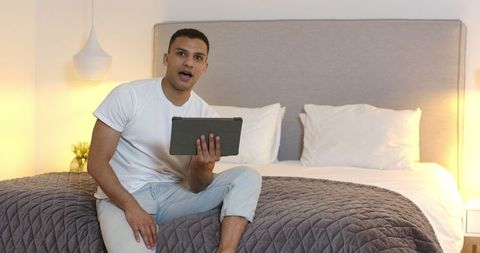 Man Video Calling While Sitting on a Bed with Tablet