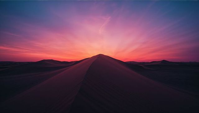 Vibrant Sunset Over Sand Dunes with Striking Horizon