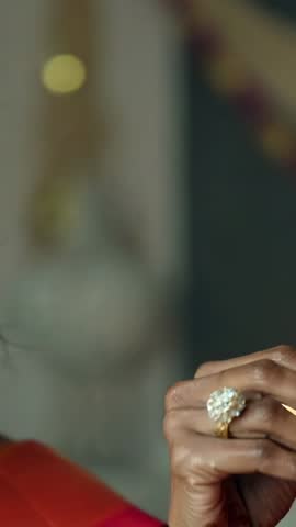 Indian bride applying sindoor and bindi at vanity wearing red sari and gold jewelry