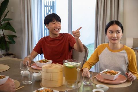 Asian couple enjoying meal and laughing in modern dining room