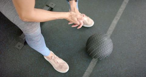 Athletic Woman Prepping for Workout with Medicine Ball in Gym