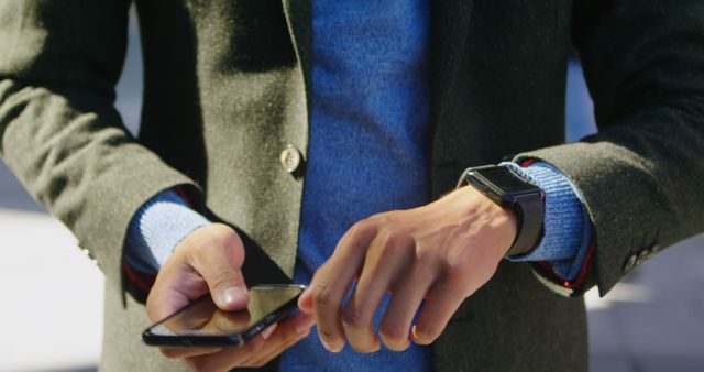 Hands of biracial man in suit using smartphone. Communication and technology, city living and lifestyle.