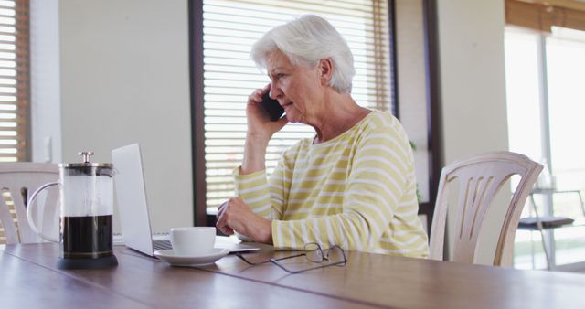 Senior Woman Working on Laptop While Talking on Phone in Cozy Home Setting - Download Free Stock Images Pikwizard.com