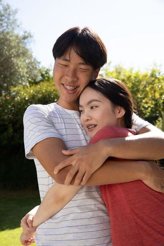 Joyful Outdoor Embrace of Young Couple in Sunlit Backyard