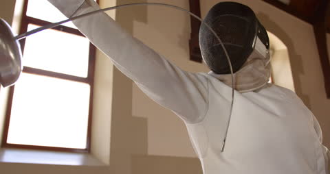 Dynamic fencing duel in bright gym setting with focus on athlete