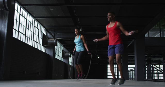 African american man and woman skipping rope in an empty urban building. urban fitness and healthy lifestyle.