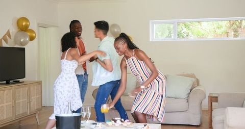 Friends Celebrating Together at Home with Drinks and Snacks