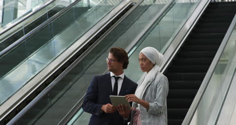 Diverse Business Professionals Discussing On Escalator In Modern Office