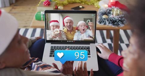 Multigenerational family sharing holiday joy on video call with santa hats and social likes