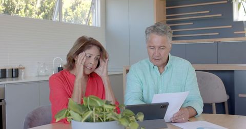 Senior couple analyzing financial documents in modern home