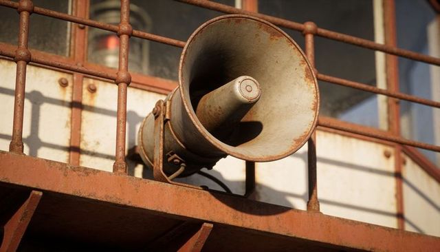 Rusted horn loudspeaker sitting on industrial metal balcony catching warm sunlight