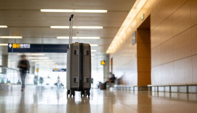 Standing hard-shell suitcase with extended handle on shiny airport terminal floor