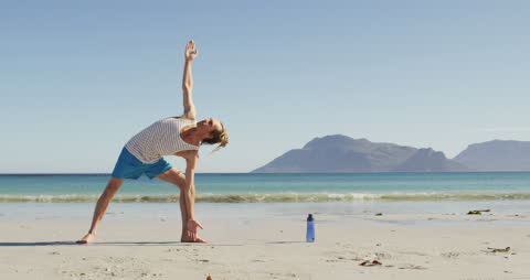 Caucasian Man Practicing Yoga on Sunny Beach with Mountain View
