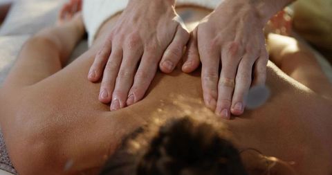 Massage therapist applying relaxing back massage on woman in tranquil spa environment