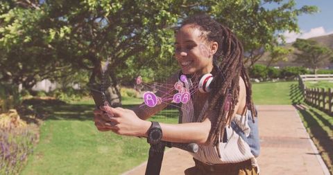 Woman riding electric scooter in park utilizing connectivity