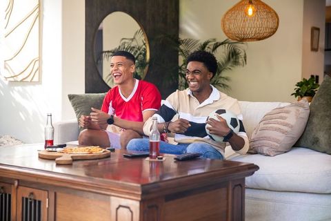 Friends enjoying soccer game with pizza in living room vibe