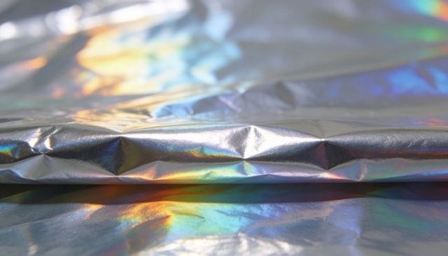 Shimmering iridescent foil with horizontal ridge and rainbow creases, holographic metallic