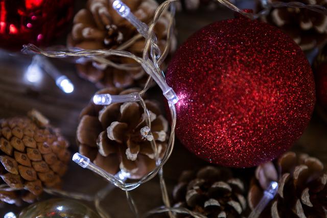 Close-up of rice lights, bauble ball and pine cone during christmas time