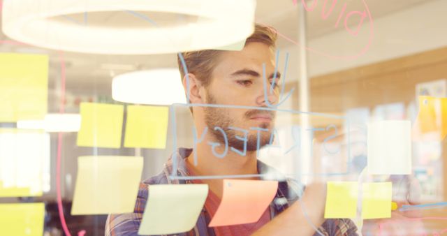 Focused Businessman Planning Strategy with Sticky Notes and Glass Board - Download Free Stock Images Pikwizard.com