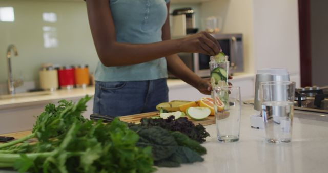Midsectin of african american attractive woman preparing smoothie in kitchen. healthy nutrition and lifestyle at home.
