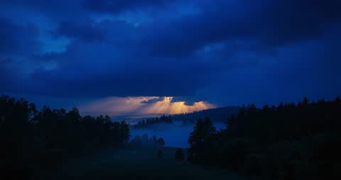 Sunlight Breaking Through Storm Clouds Over Misty Forest at Twilight