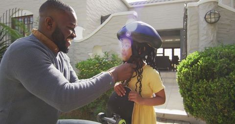 Father Helping Daughter Wear Helmet for Skateboarding