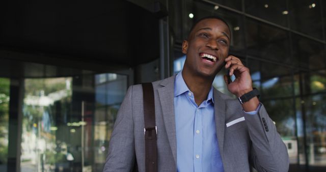 Smiling african american businessman using smartphone outside of modern office building. business and business people in office concept.