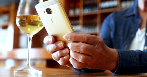 middle-aged enjoying wine while checking smartphone at cozy bar - Download Free Stock Images Pikwizard.com
