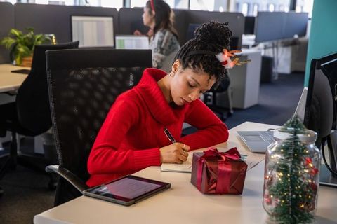 African american woman writing at decorated office desk during holiday season