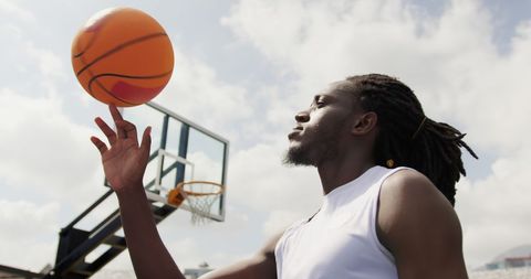 Athletic man balancing basketball outdoor