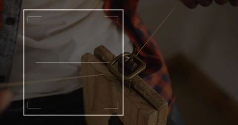Craftsman threading leather strap on wooden workbench