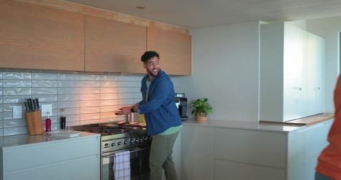 Man cooking with partner at stainless-steel stove in bright modern kitchen