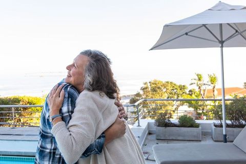 Senior Couple Embracing on Sunny Poolside Terrace