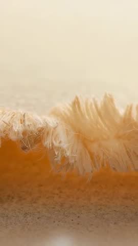 Vertical Macro Video of Frayed Beige Fringe Lifting and Settling on Sandy Surface