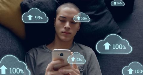 Young Man Relaxing with Smartphone and Digital Cloud Symbols
