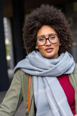 African american woman wearing glasses and checked scarf standing in urban corridor portrait