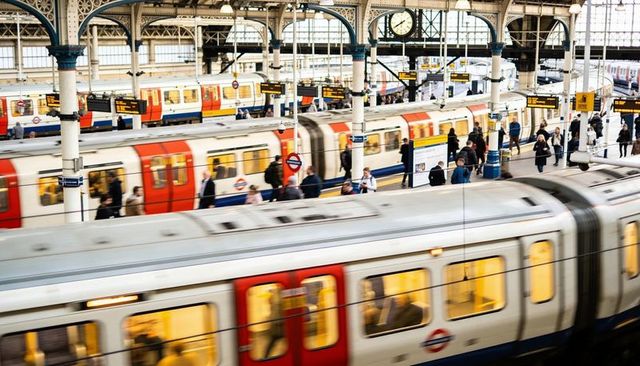 Blurred commuter trains racing through busy london underground station with rushing crowd