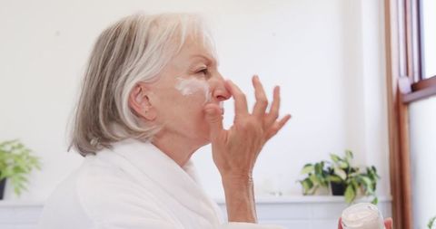 Senior Woman Applying Facial Cream Demonstrating Self-Care and Wellness