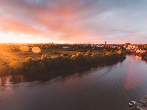 Sunset River Landscape Glowing with Golden Light Over Riverside Town and Rowers