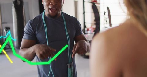 Trainer coaching client pointing and demonstrating jump rope technique with neon lines