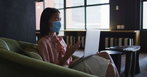 Asian Businesswoman Wearing Face Mask for Virtual Meeting in Modern Office