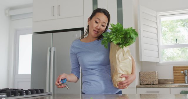 Woman Holding Groceries While Talking On Phone In Kitchen - Download Free Stock Images Pikwizard.com