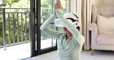 African american woman practicing vr meditation on yoga mat near sunny balcony wellness