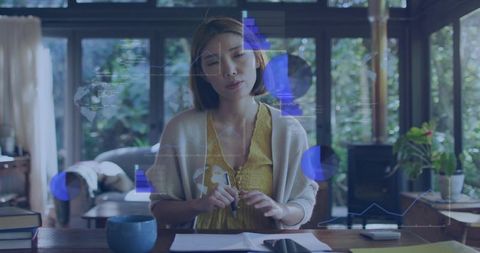 Chinese woman analyzing augmented reality charts at home desk working remotely