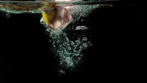 Hand Reaches for Lemon Underwater with Splashing Bubbles